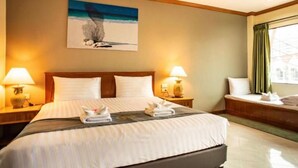 A hotel room with a large bed, two bedside lamps, a painting on the wall, and a window with curtains. - Royal Vista (Patong)