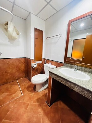 A bathroom with a toilet, sink, and mirror. - Royal Vista (Patong)