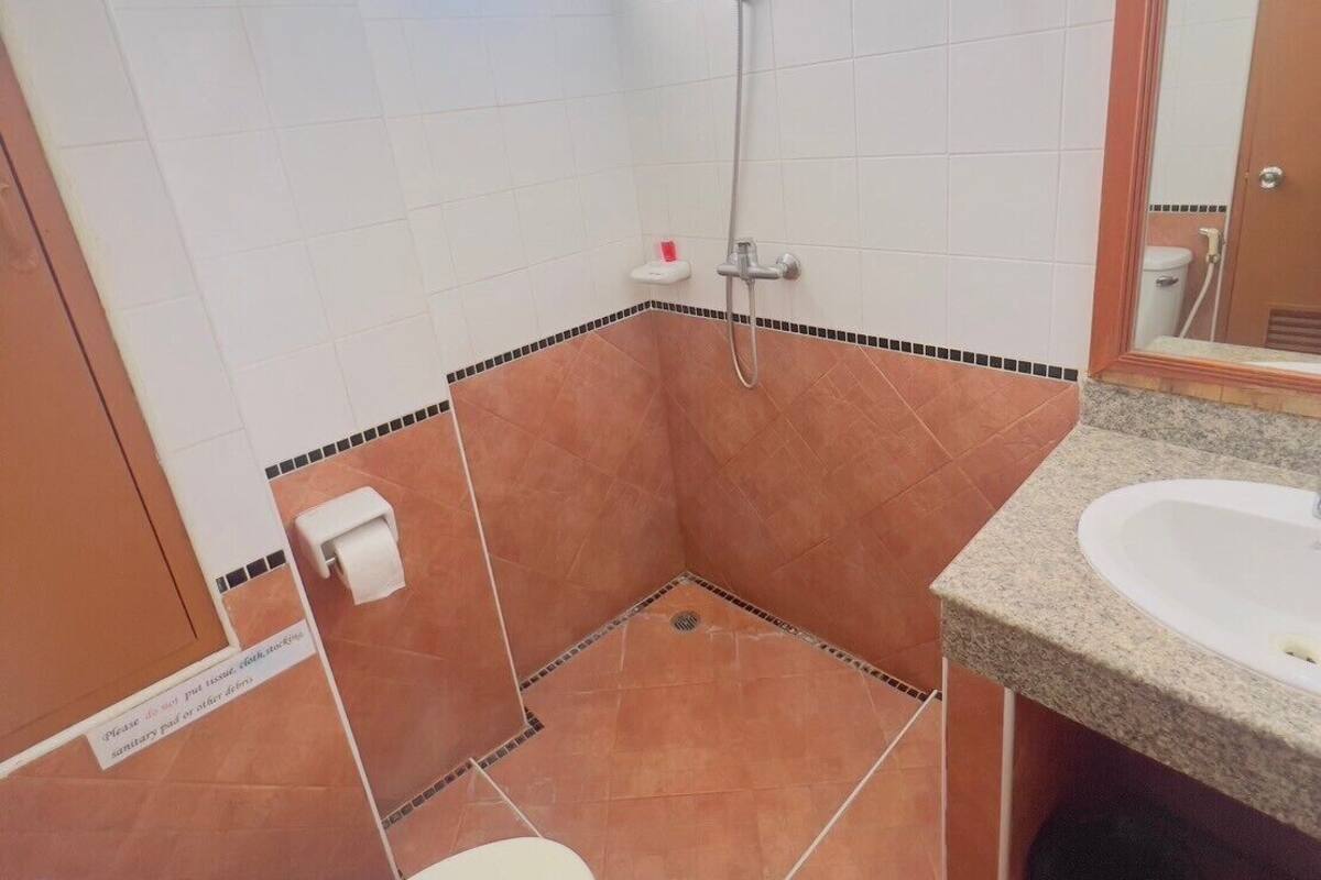 A bathroom with a shower, toilet, sink, and a window.