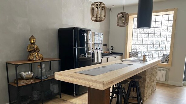 A modern kitchen with a wooden island, black appliances, and a decorative Buddha statue. - Nice apartment in the center of Santander (Santander)