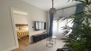 A modern bedroom with a bed, a TV, a console table, and a large window with curtains. - Nice apartment in the center of Santander (Santander)