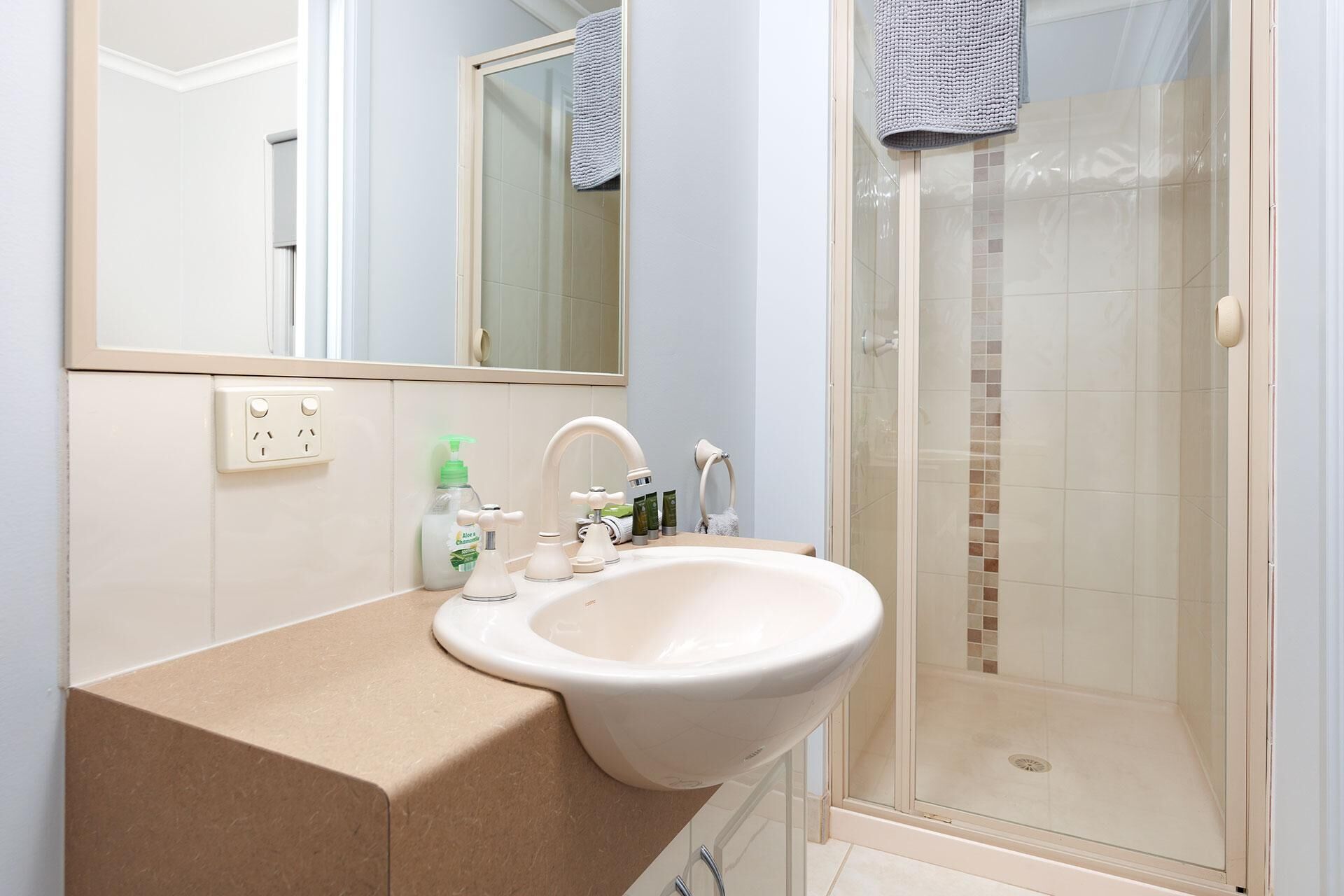 Un bagno con lavandino, specchio e doccia.