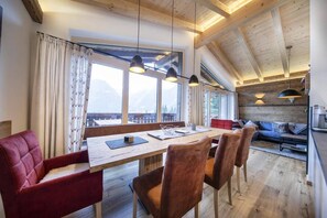 A dining area with a wooden table, red upholstered chairs, and pendant lighting.