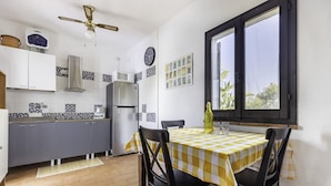 Eine kompakte Küche mit modernen Geräten, ein Essbereich mit kariertem Tischlein und ein Fenster mit Blick.