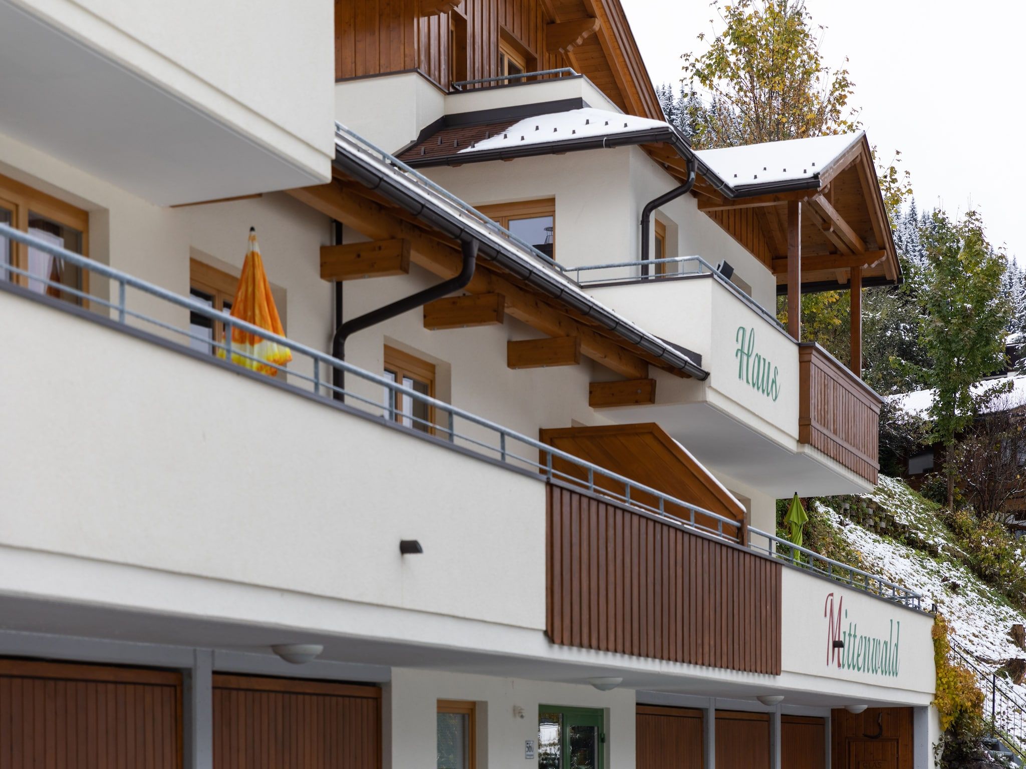 A multi-story hotel with wooden balconies and a sign that reads 'Haus Mittenwald.'