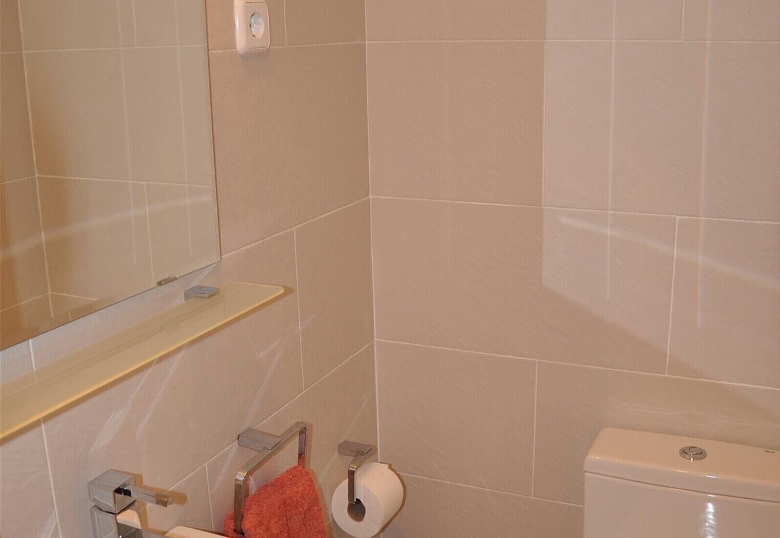 A bathroom with a toilet, a sink, a mirror, and a towel rack.