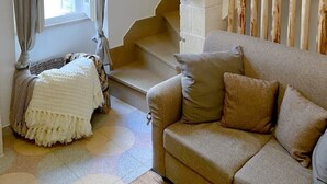 Un accogliente soggiorno con un divano color beige, una scala e una parete decorativa con elementi in legno e opere d'arte.