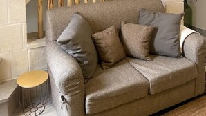 Un soggiorno con un divano grigio, un pannello divisorio in listelli di legno e corna decorative alle pareti.