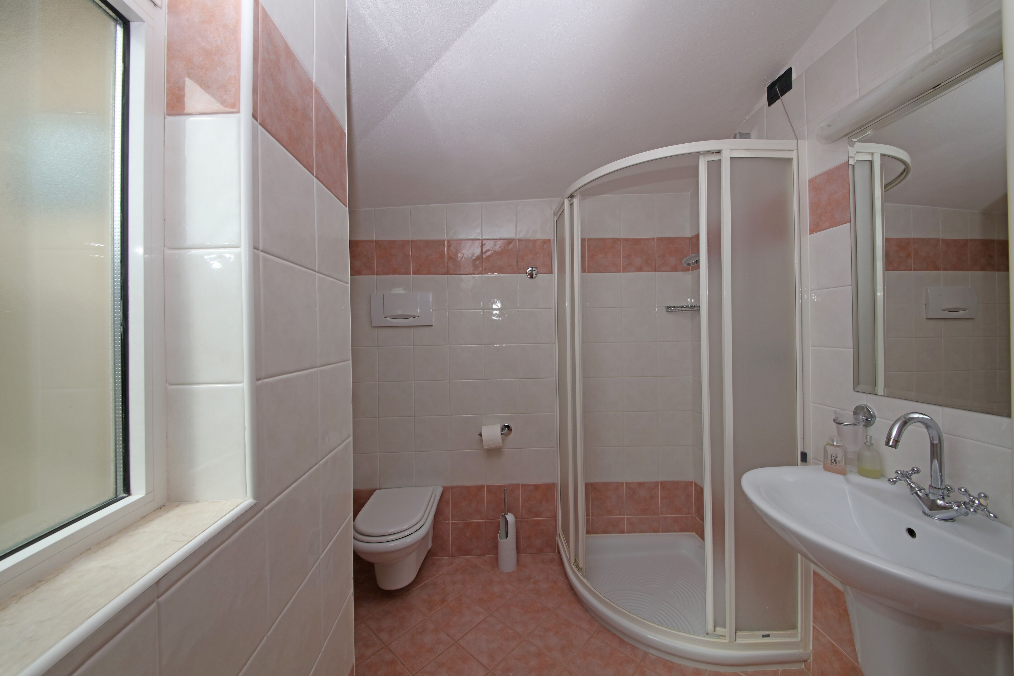 A bathroom with a toilet, shower, and sink.
