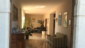 Un vaste espace de vie doté d’un sol à carreaux, d’une armoire en bois, d’un canapé à rayures et de plusieurs plantes en pot.