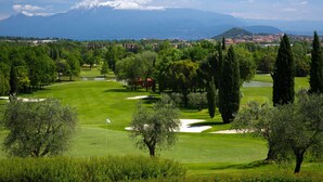 Un parcours de golf offrant une vue sur des montagnes enneigées en arrière-plan.