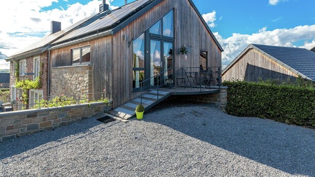 A modern house with a sloped roof, large windows, and a stone foundation. - La Roche Cozy Forest Escape (Marcouray)