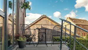 A wooden deck with metal chairs and a table, a metal staircase, and a wooden fence. - La Roche Cozy Forest Escape (Marcouray)