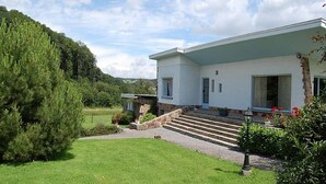 Ein modernes, zweistöckiges Haus mit gepflegtem Rasen und einer Steintreppe, die zum Eingang führt.