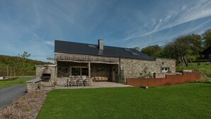 A modern house with a stone exterior, a large patio, and a chimney.