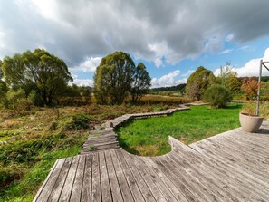 A wooden boardwalk leading through a grassy field with trees and a cloudy sky. - Bertrix charming 2-bedroom holiday home (Bertrix)