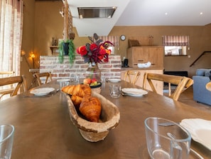 A dining area with a wooden table, chairs, a vase with flowers, and a brick wall. - Bertrix charming 2-bedroom holiday home (Bertrix)