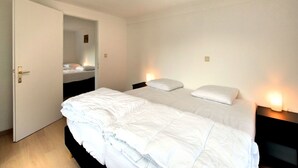 A hotel room with a large bed, a door leading to a bathroom, and a ceiling light.