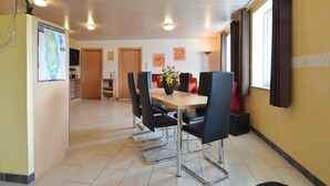 A dining area with a wooden table and black chairs, a map on the wall, and a window with curtains. - Holiday Home in Burg Reuland (Burg Reuland)