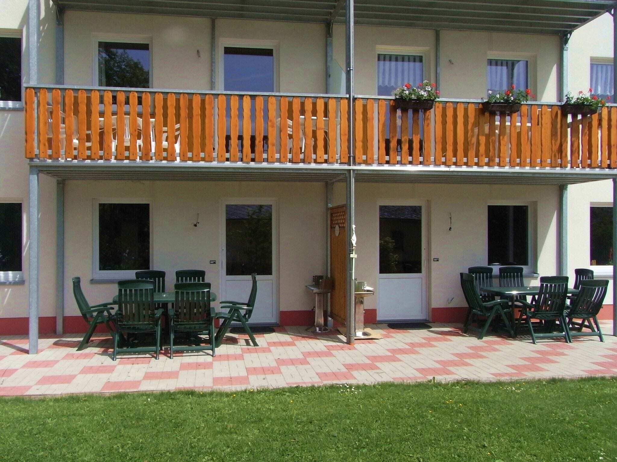 A two-story building with a balcony, outdoor seating area, and a checkered floor.