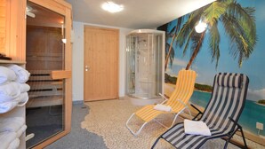 A room with a sauna, two sun loungers, a glass-enclosed shower, and a tiled floor. - Holiday Home in Burg Reuland (Burg Reuland)