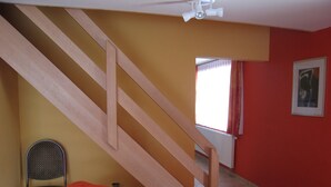 A room with a wooden staircase, a chair, and a bed.