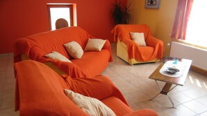 A living room with a sofa and armchairs, a coffee table, and a radiator.