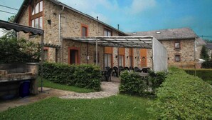 A stone building with a covered patio area, outdoor seating, and a small garden.