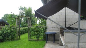 A patio area with a concrete floor, a metal pergola, and a stone wall.