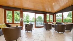 A spacious room with a high ceiling and large windows offering a view of the outdoors.