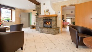 A spacious living area with a stone fireplace, leather sofas, and a view of the dining area.