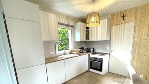 Una cocina moderna con armarios blancos, horno integrado y ventana que proporciona luz natural.