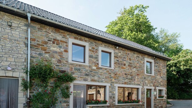 A stone building with three windows, a door, and a small porch area with potted plants. - Modern Cottage with Private Garden in Waimes (Waimes)
