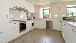 A modern kitchen with white cabinets, a stove, oven, microwave, and dishwasher. - Modern Cottage with Private Garden in Waimes (Waimes)