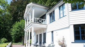 Un bâtiment blanc à deux étages, doté d’un balcon et d’un porche abrité.