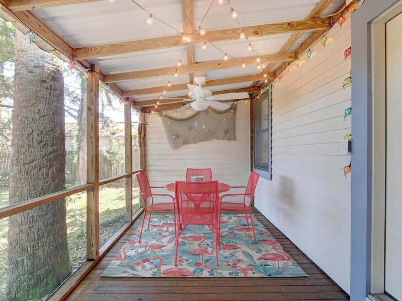 Una veranda coperta con soffitto in legno, una ventola a soffitto e un tavolo con sedie.