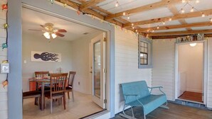 A cozy room with a wooden ceiling, a dining area with a table and chairs, a bench, and a door leading to another room. - Marsh Magic 2 Bed 1 Bath Beach House w Marsh View (Tybee Island)