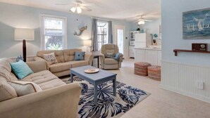 A spacious living room with a beige sofa set, a blue coffee table, and a patterned rug. - Marsh Magic 2 Bed 1 Bath Beach House w Marsh View (Tybee Island)