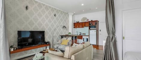 A living room with a TV, sofa, and a small table with a plant.