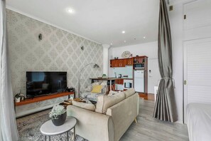 A living room with a TV, sofa, and a small table with a plant. - Viaduct Studio w/ Balcony Close to Ferry by Zodiak (Auckland)