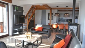 Een moderne woonkamer met een open haard, een eetgedeelte en een keuken.