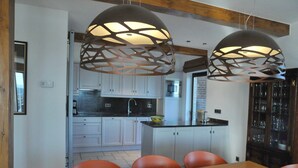 Een moderne keuken met witte kasten, een centraal eiland en hanglampen.