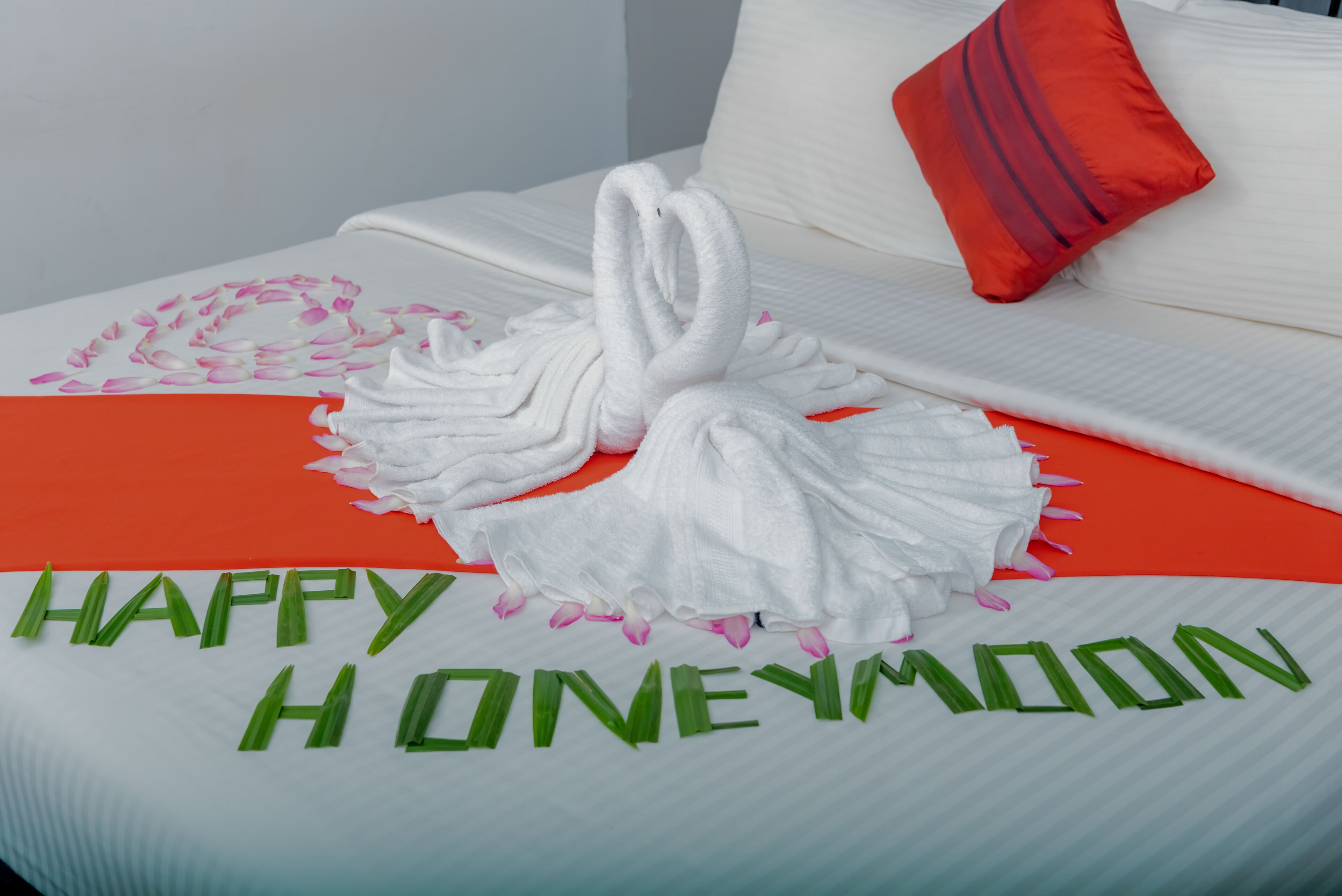 Un lit décoré avec des serviettes pliées en forme de cygnes et un message indiquant « Joyeuse lune de miel ».