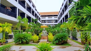A courtyard with a Buddha statue, surrounded by lush greenery and potted plants. - New Riverside Hotel (Siem Reap)