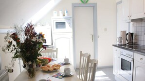 En matplats med ett bord dukat för två personer, en vas med blommor och en bit vattenmelon.