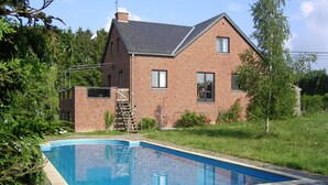 Ett tvåvåningshus byggt av tegel med en swimmingpool.