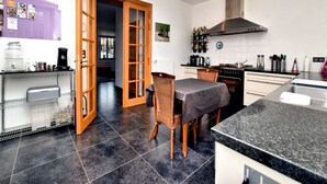 A modern kitchen with a dining area, featuring a large island, a built-in oven, and a coffee machine. - Countryside Escape for 9 (Honnay)