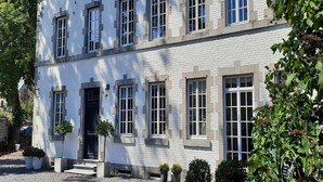A two-story building with a symmetrical facade, evenly spaced windows, and a central entrance with steps leading up to it. - Countryside Escape for 9 (Honnay)