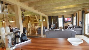 Una cocina moderna con encimera de madera, una cafetera y un hervidor. Se ve una escalera que sube a un nivel superior.