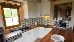 Una cocina moderna con armarios blancos, encimera de madera, lavavajillas y ventana con vistas a zonas verdes.